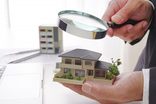 家の模型と虫めがねの画像