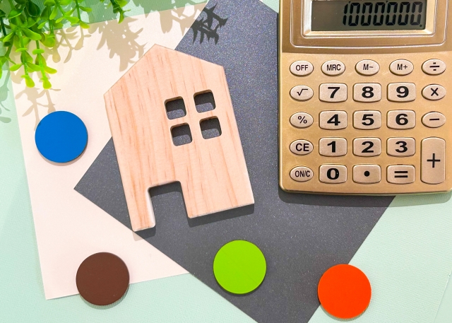 alt="住宅の価格をイメージさせる家型オブジェと電卓|いえとち本舗(池田建設)の坪単価を考えるイメージ画像"